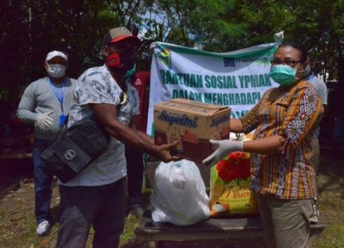 Sekertaris YPMAK Johanna Julianan Saidui menyerahkan bahan makanan kepada Kepala Kampung Utikini Dua Marinus Kogoya