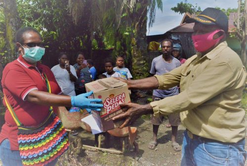 Karyawan YPMAK Marina Beanal menyerahkan bahan makanan kepada masyarakat.